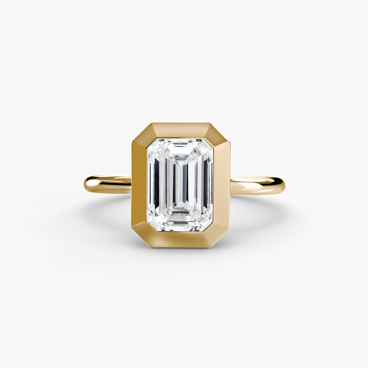 The Bezel Set Solitaire engagement ring in yellow gold with an emerald-cut centre stone
