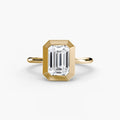 The Bezel Set Solitaire engagement ring in yellow gold with an emerald-cut centre stone