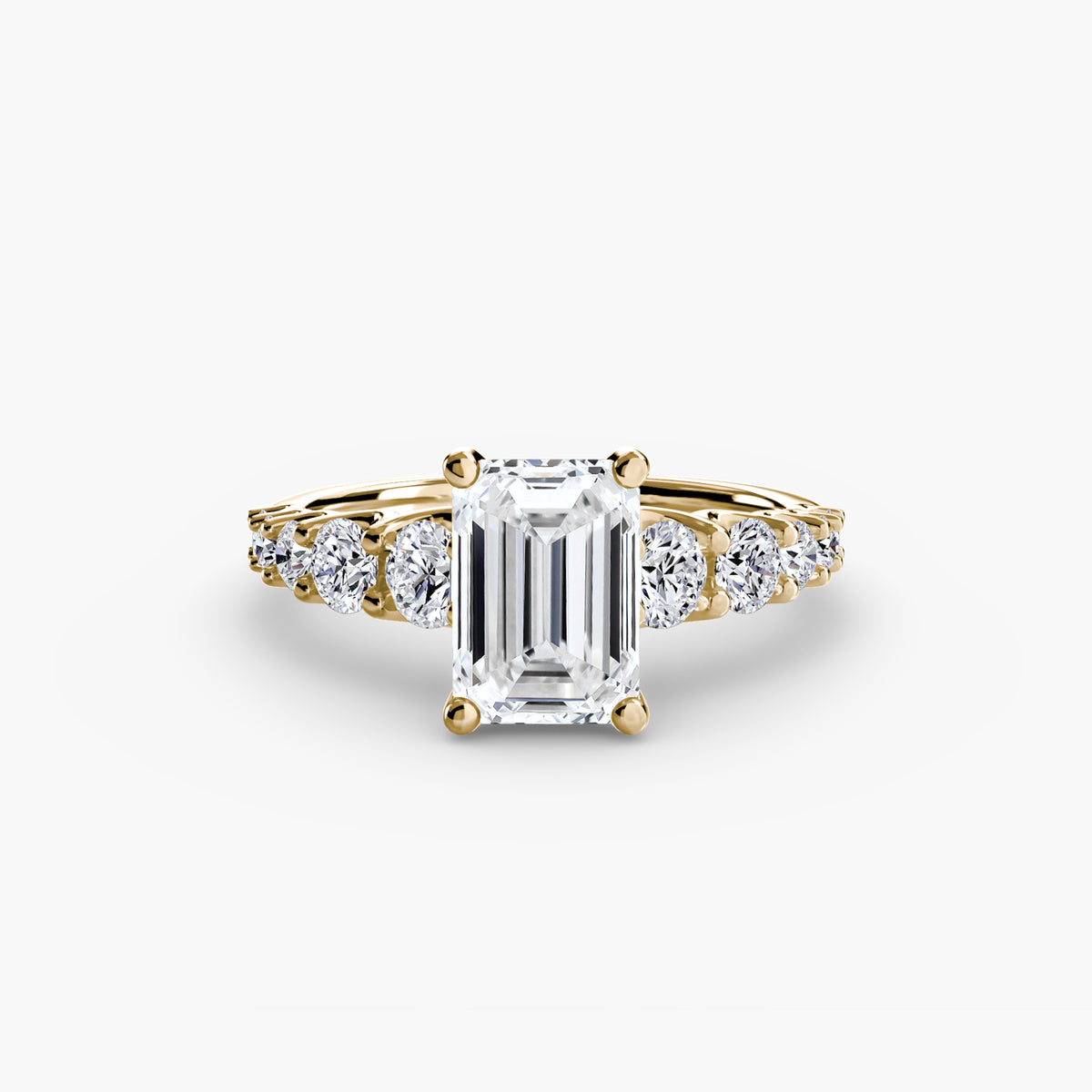 The Graduated Accent Ring in yellow gold with an emerald-cut centre stone