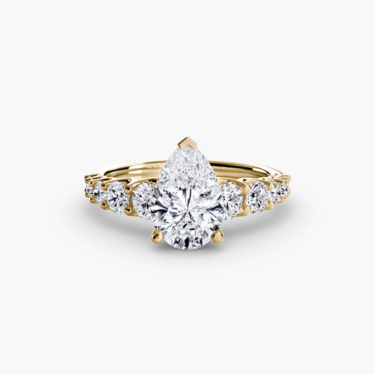 The Graduated Accent Ring in yellow gold with a pear-shaped centre stone