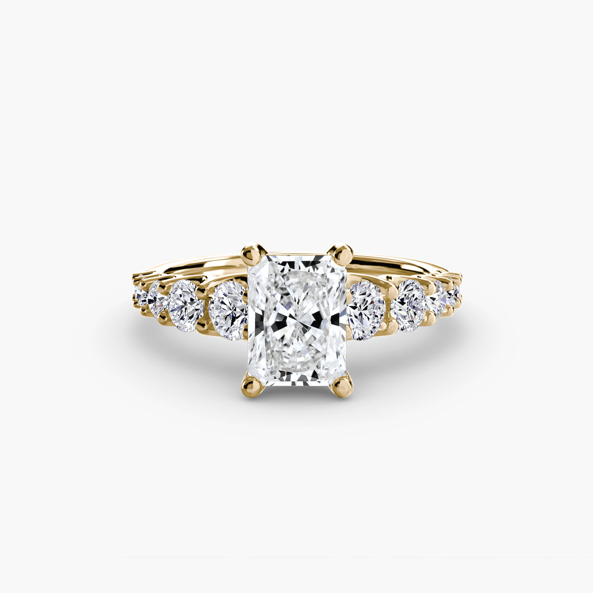 The Graduated Accent Ring in yellow gold with a radiant-cut centre stone